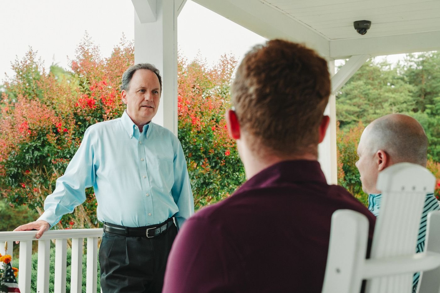 Chris Parker talking with neighbors on a porch